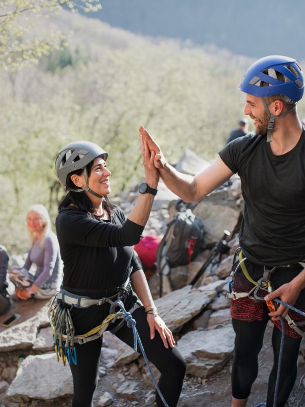 A group of seniors with instructor climbing rocks outdoors in nature, active lifestyle.